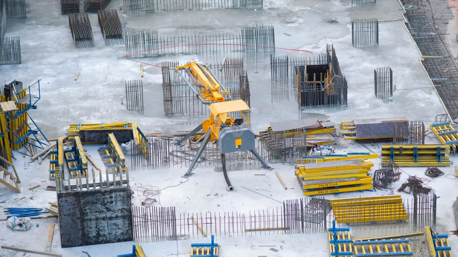 Rebar cages, column formwork and a concrete pump on a concrete deck under construction