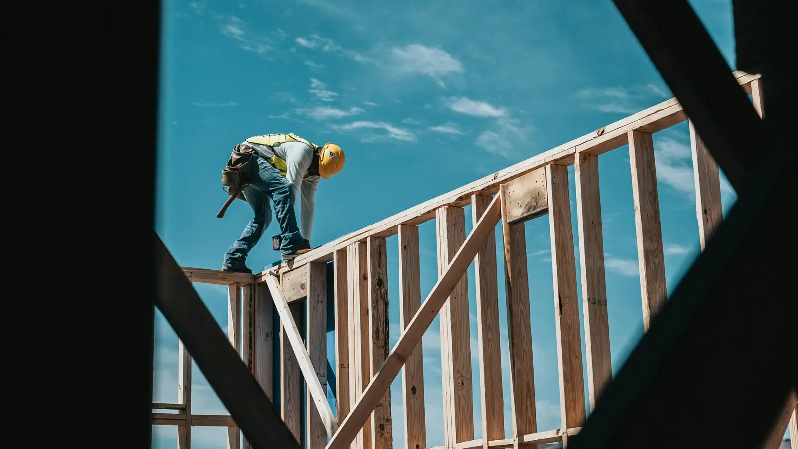Framer in a hard hat working on top of a wood stud wall