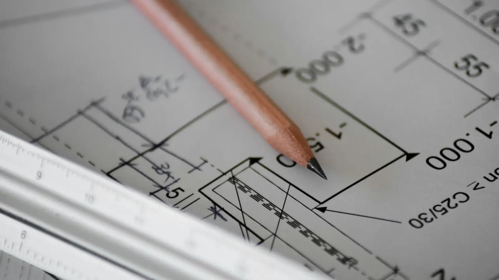 Pencil resting on a dimensioned construction drawing next to a scale ruler